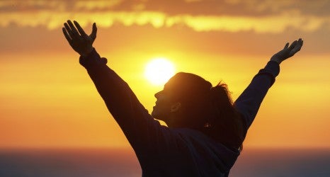 Woman praising and enjoying golden sunset
